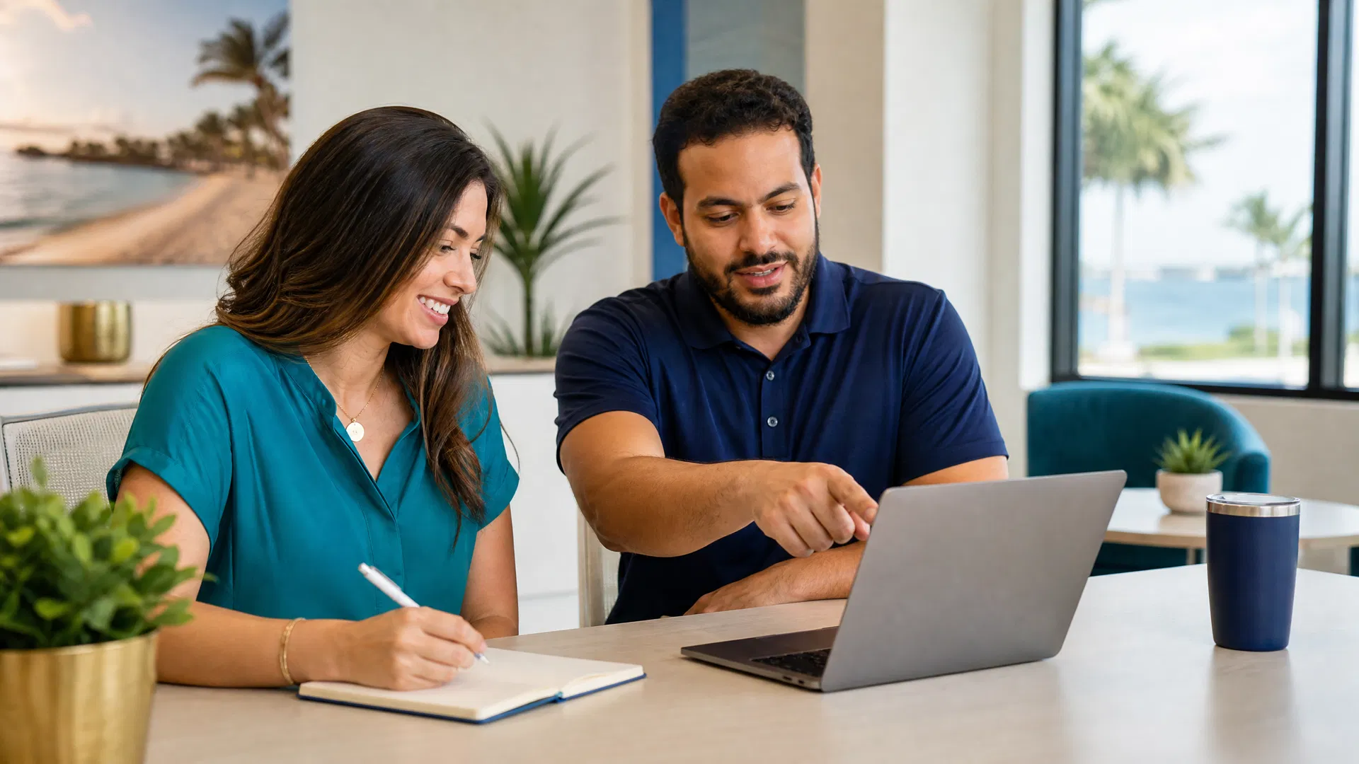 Two marketing professionals reviewing AI-powered SEO content strategy on a laptop in a sunlit Southwest Florida office with palm trees visible through the window